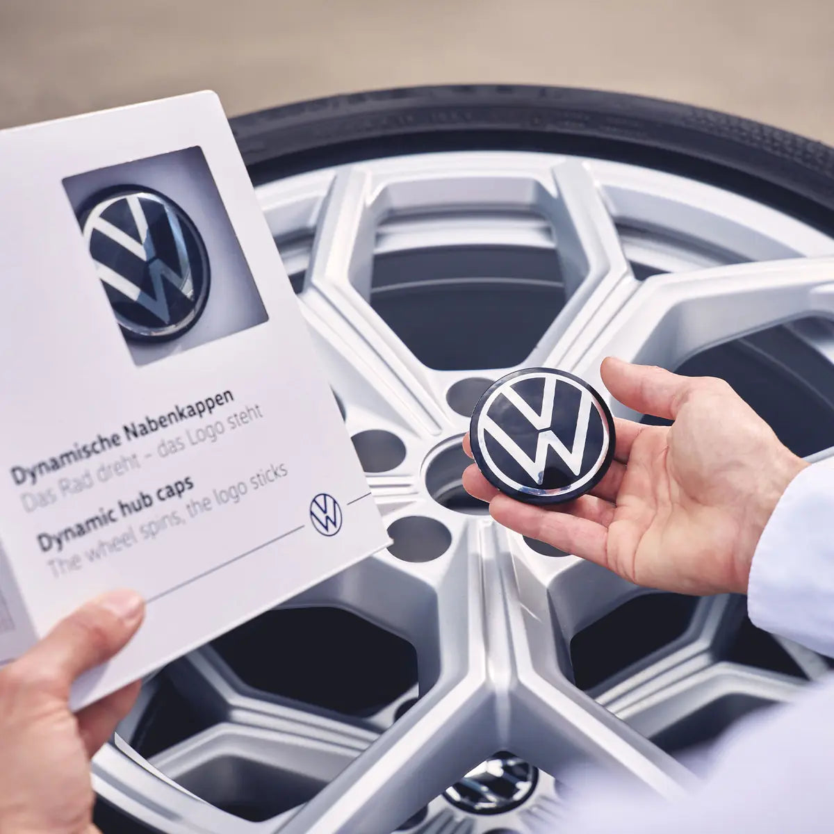 Original Volkswagen Nabenkappen für Alufelgen mit VW Logo in der Hand