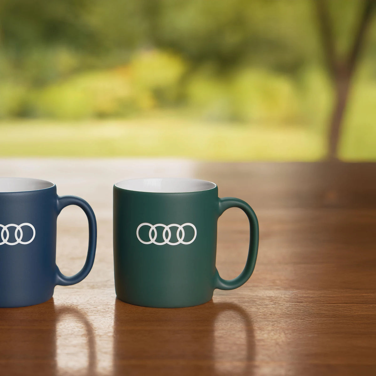 Audi Tassen der Audi collection im Vergleich, grau-grüne Porzellantasse 3292500600 auf Holztisch
