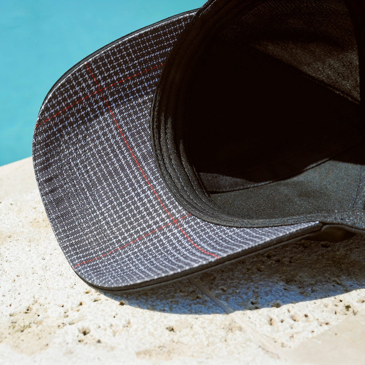 Detail des GTI Basecaps mit kariertem Innenschirm auf einem Steinrand am Pool, 3A5084300A041