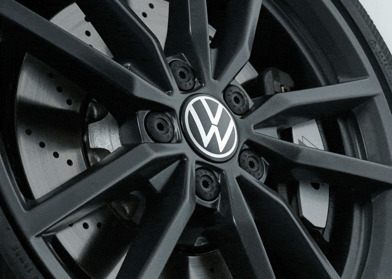 Drehende schwarze Felge eines VW R, bei der das VW Logo der Nabenkappe stillsteht, 10A071213A