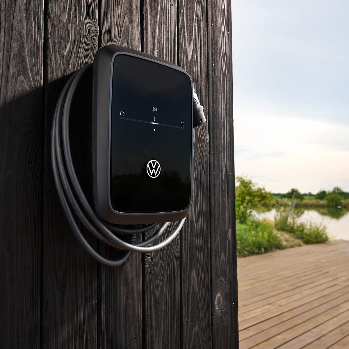 VW ID. Charger Connect 2 Wallbox an dunkler Holzwand einer Terrasse am See montiert